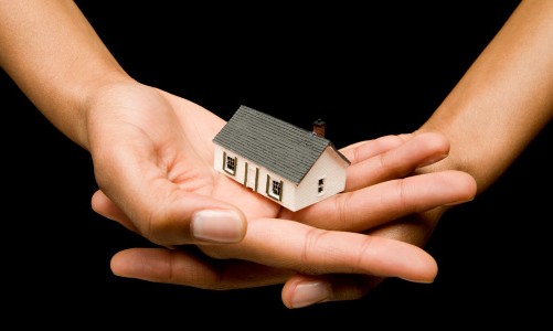 Human hands holding small house