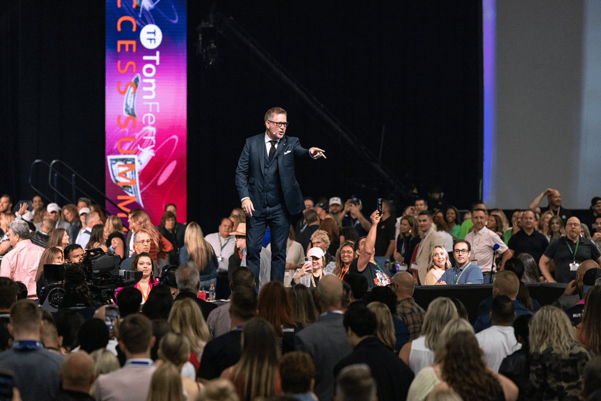 Tom Ferry on stage pointing at a crowd