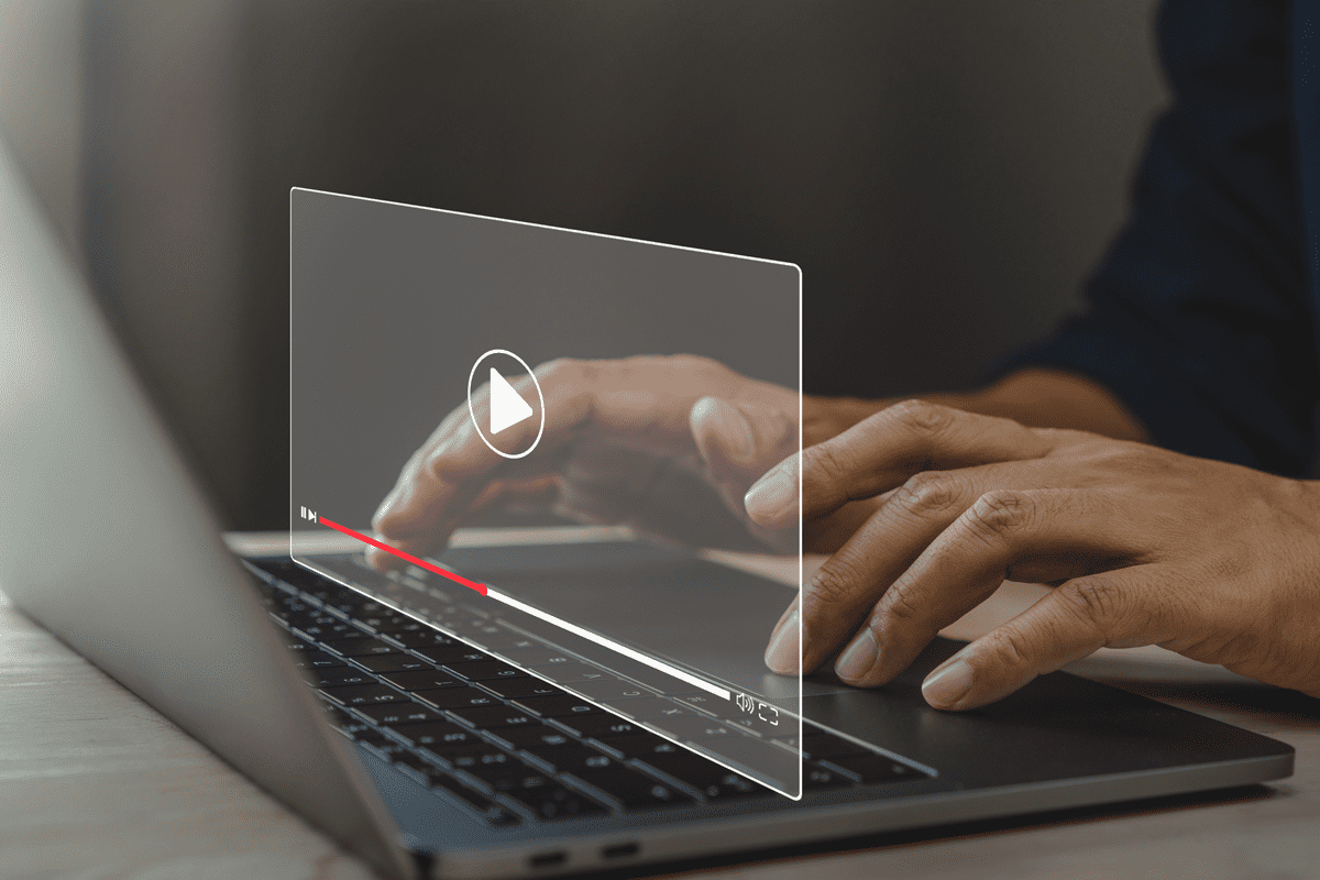 someone on a laptop with a graphic design of a video hovering over keyboard