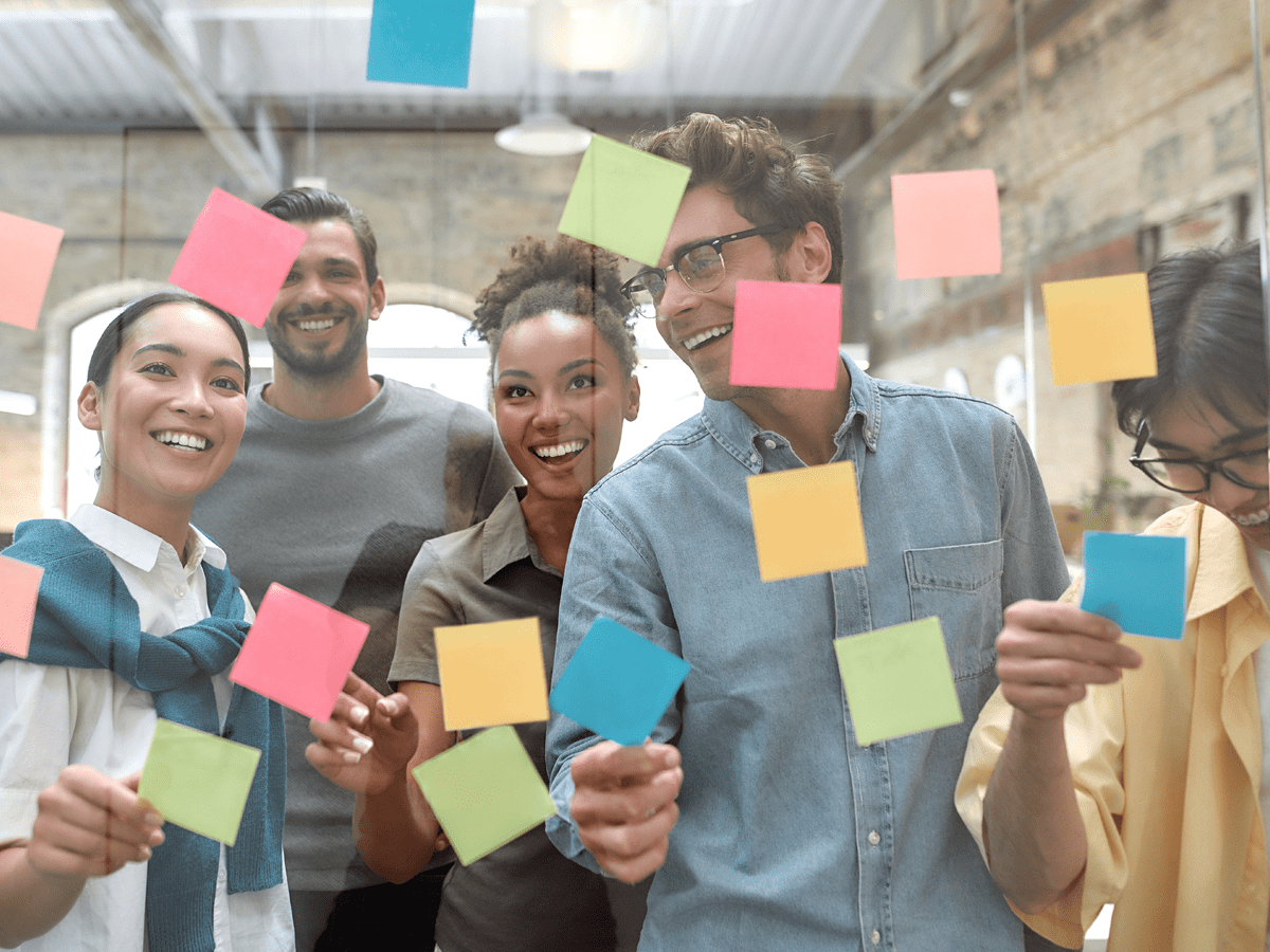 group of people in front of a glass window looking at post it notes