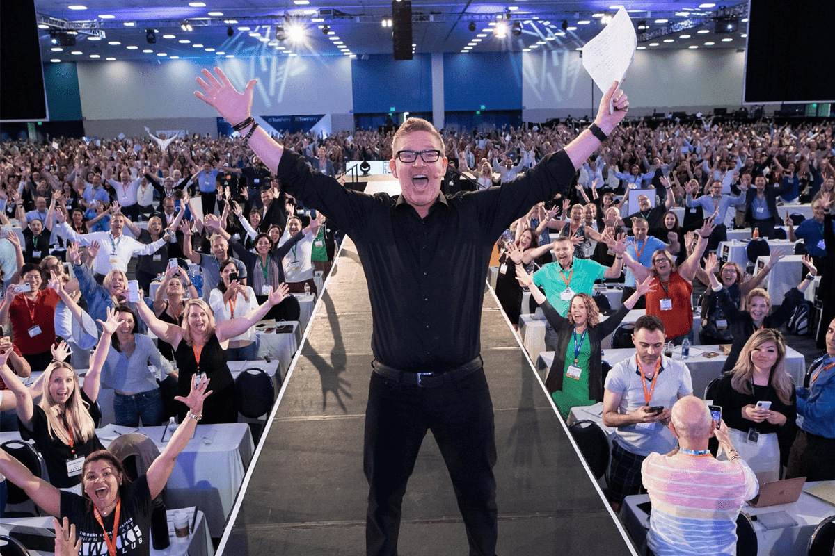 Tom Ferry on stage pointing at a crowd